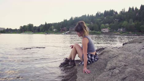 Cute-hipster-girl-sitting-down-by-the-edge-of-the-water