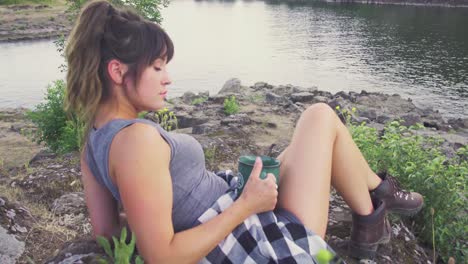 Cute-hipster-girl-drinking-from-a-mug-and-relaxing-by-the-water