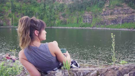 Cute-hipster-girl-lounging-and-drinking-from-a-mug-in-front-of-the-water