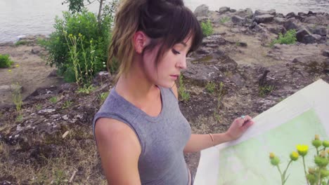 Cute-hipster-girl-looking-at-a-paper-map-of-the-park-she-is-exploring