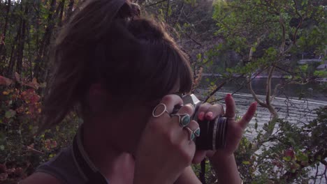 Cute-hipster-girl-talking-and-then-holding-up-a-film-camera-with-a-lens-flare
