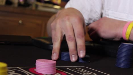 Close-up-shot-of-a-male-hand-fidgeting-unmarked-casino-chips-at-a-game-table-with-some-handheld-camera-movement