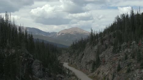 Aerial-dolly-of-creek-and-road-with-mountain-peak-in-background-in-Colorado
