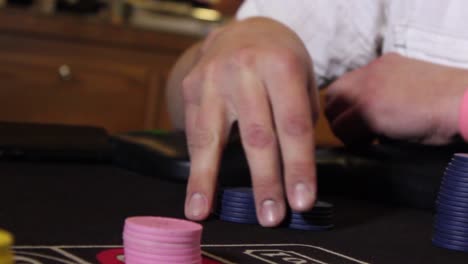 Close-up-shot-of-a-male-hand-fidgeting-unmarked-casino-chips-at-a-game-table-with-slow-pan-tilt-camera-movement