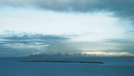 Zeitraffer-Des-Sonnenlichts-Durch-Wolken,-Die-Sich-Im-Januar-über-Einen-Schneebedeckten-Berg-In-Island-Bewegen