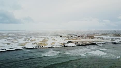 Aerial-shot-of-Sandgerdi,-Iceland-coast-flying-closer-to-shore-in-January