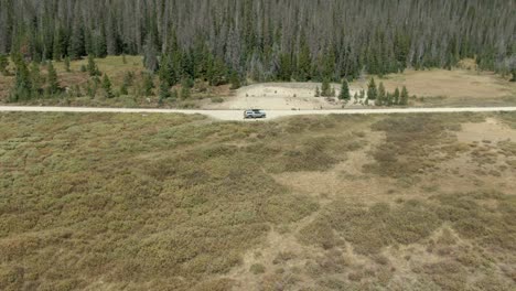 Aerial-of-guy-piloting-drone-in-Colorado-national-forest-standing-next-to-truck