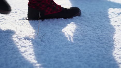 Red-plaid-snow-boots-walk-through-untouched-snow-in-slow-motion