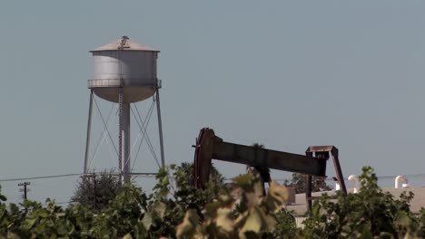 Oil-pump-in-vineyard-with-water-tower-in-California