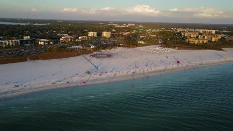 Aerial-shot,-slow-approach-to-scenic-white-sandy-beaches-over-turquoise-water-on-siesta-key-beach-Florida-with-drum-circle