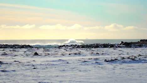 Slow-motion-shot-of-large-wave-breaking-in-distance-in-Iceland-in-the-winter-during-a-bright-day