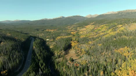 Aerial-pan-across-road-with-car-and-mountain-forest