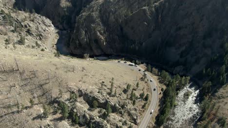 Aerial-over-road-in-canyon-next-to-river-with-cars-driving-in-Colorado