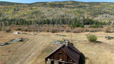 Dolly-up-from-cabin-in-field-to-fall-colors-on-mountain