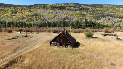 Dolly-backwards-of-cabin-in-field-with-fall-colors-in-background