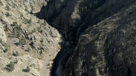 Aerial-over-road-in-canyon-next-to-river-following-cars-in-Colorado