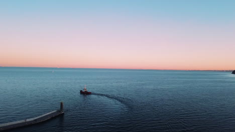 Drohne-Fliegt-über-Fischerboot,-Das-Bei-Sonnenuntergang-Aus-Der-Bucht-Segelt