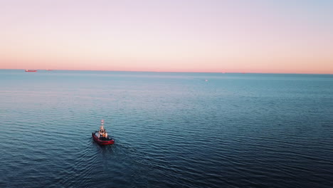 Drone-flying-around-fishing-boat-sailing-on-the-sea-at-the-sunset