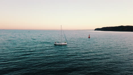 Drone-flying-above-the-yacht-sailing-into-the-bay-at-the-sunset