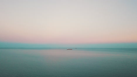 Drohne-Fliegt-über-Dem-Meer-Mit-Dem-Frachtschiff-Im-Hintergrund-Bei-Sonnenuntergang-1