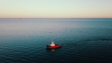 Drone-flying-above-the-fishing-vessel-sailing-on-the-sea-at-the-sunset