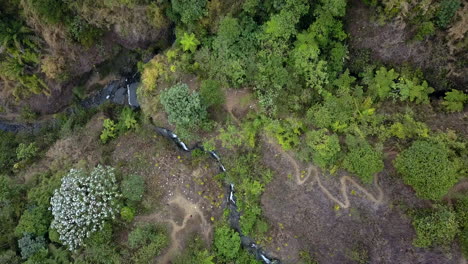 Luftdrohnenansicht-Eines-Waldes-In-Ecuador-Mit-Einem-Fluss,-Der-Von-Einem-Wasserfall-Und-Einer-Ländlichen-Unbefestigten-Straße-Kommt