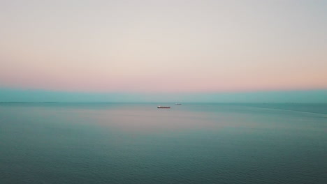 Drohne-Fliegt-über-Dem-Meer-Mit-Dem-Frachtschiff-Im-Hintergrund-Bei-Sonnenuntergang