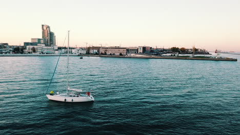 Drone-flying-over-yacht-sailing-into-the-bay-at-the-sunset