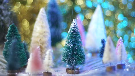 Slow-motion-snow-glitter-drops-on-retro-bottle-brush-tree-forest-with-blue-and-gold-bokeh