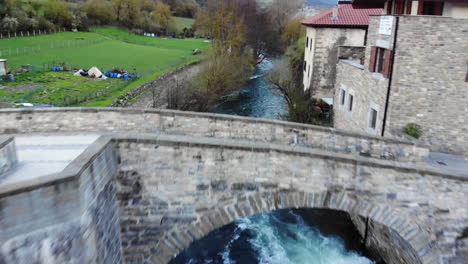 Aerial-footage-of-Stone-European-Bridge-over-Rushing-River