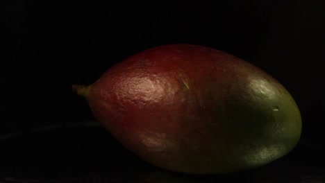 Close-Up-Of-Spinning-Mango-Fruit-On-a-Black-Background