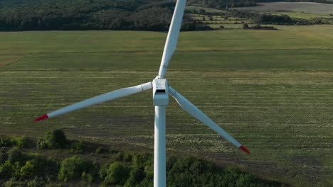 Aerial-drone-shot-around-single-wind-turbine-generator-in-grass-field