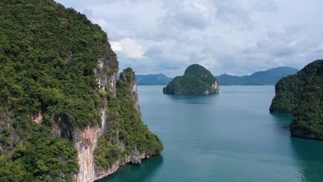 Drone-footage-of-islands-in-Thailand-with-limestone-rock-formation-sticking-out-of-the-water-and-the-ocean-in-background-7