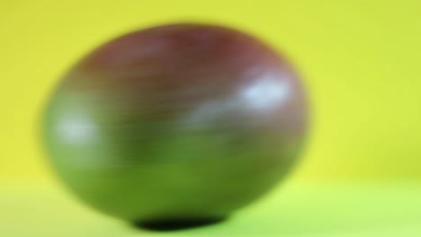 Close-Up-Of-Spinning-Mango-Fruit-On-a-Yellow-Background