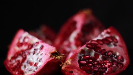 Geschnittene-Granatapfelfrucht-Und--samennahaufnahme-Auf-Schwarzem-Hintergrund