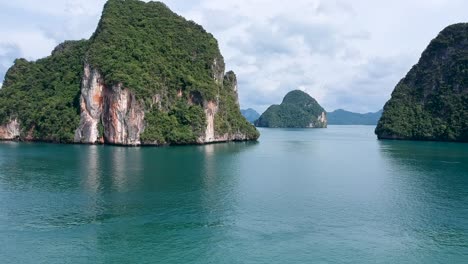 Drone-footage-of-islands-in-Thailand-with-limestone-rock-formation-sticking-out-of-the-water-and-the-ocean-in-background-12