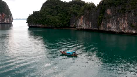 Drohnenaufnahmen-Von-Longtail-Booten,-Die-Um-Die-Inseln-Thailands-Navigieren,-Mit-Kalksteinformationen,-Die-Aus-Dem-Wasser-Ragen,-Und-Dem-Ozean-Im-Hintergrund-7