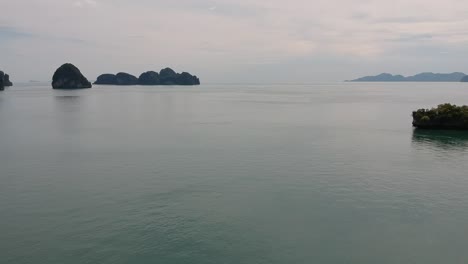 Drohnenaufnahmen-Von-Inseln-In-Thailand-Mit-Kalksteinfelsen,-Die-Aus-Dem-Wasser-Ragen,-Und-Dem-Ozean-Im-Hintergrund