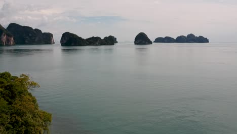 Drone-footage-of-islands-in-Thailand-with-limestone-rock-formation-sticking-out-of-the-water-and-the-ocean-in-background-3