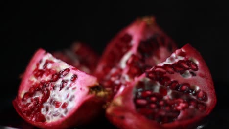 Close-Up-Cutted-Pomegranate-Fruit-And-Seeds-On-Black-Background
