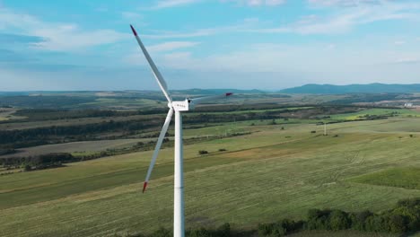Aerial-panoramic-shot-around-single-wind-turbine-generator-in-grass-field