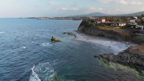 Aerial-panning-shot,-drone-fly-around-seashore-cliffs-and-beach-houses