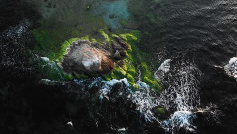 Bogenluftaufnahme-über-Felsen-Im-Meer-Bei-Sonnenuntergang,-Hellen-Farben-Und-Dunklem-Wasser