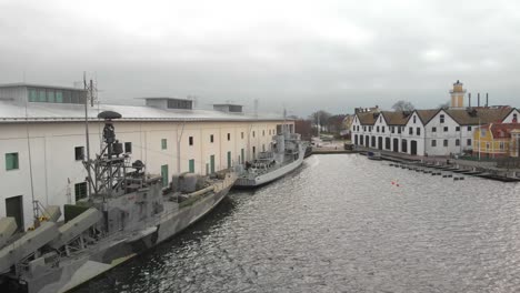 Low-alititude-aerial-footage-from-the-side-of-two-military-ships-next-to-a-museum-in-Karlskrona,-Sweden