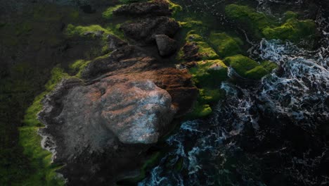 Rise-and-rotate-aerial-shot-over-rock-in-the-sea-at-sunset