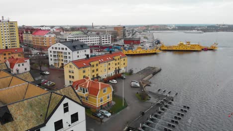 Aerial-footage-over-Karlskrona,-Sweden-focusing-three-yellow-ferries-and-old-houses