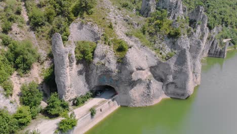 Panning-aerial-footage-of-beautiful-cliffs-with-road-tunnels-surrounded-by-lake-1