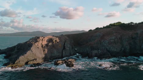 Aerial-pan-shot-of-big-seashore-cliffs-and-waves-with-drone-at-sunset