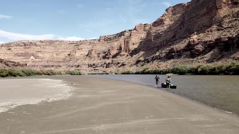 2-guys-walking-canoe-down-river-in-Utah