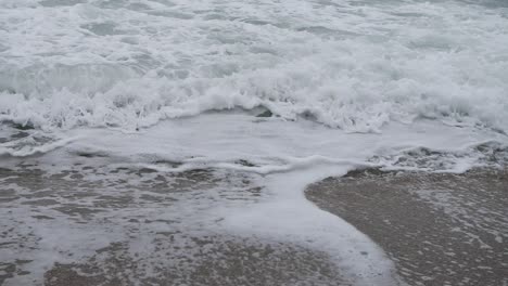 Turbulente-Schaumwellen-In-Zeitlupe,-Die-Am-Strand-Ihr-Lebensende-Erreichen
